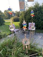 Three hanging crystal sun catchers and hummingbird dreamcatcher with colorful crystals and pewter charms by daylight outdoors.