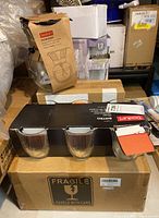 Photo showing boxed Bodum pour over coffee maker, Bodum glass mugs in a box with Fragile label visible, and additional stacked boxes.