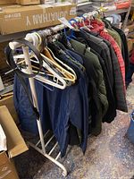 Side view of rack with various jackets and coats in navy blue, olive green, black, and red pattern.