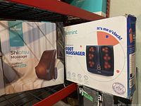 Boxes of Boriwat Shiatsu massage cushion and Belmint foot massager on shelf