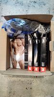 Overhead photo of opened box revealing Calvin Klein classic cotton briefs multipack, three black boxes with Medium size red labels with Speedo branding and a plastic pack of undergarments