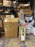 Boxes stacked with Kraft cardboard and branded packaging of cooler and BBQ tools visible, also Corona Extra drink tub and pedal bin seen in background