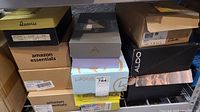 Stacked shoe boxes with visible brand names Amazon Essentials, LifeStrides, Aldo, Clarks, Queenie