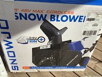 Front of open box showing Snow Joe branding and 48 V Max cordless snow blower illustration