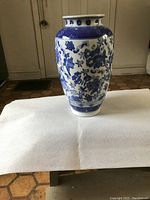 Photo showing full front view of the large Chinese porcelain vase on a white cloth background, highlighting blue floral and butterfly motifs.