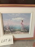 Front view of framed oil painting showing woman on shore by ocean with birds and flowers