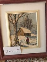 Framed oil painting showing a person walking in snow towards a cabin, signed 'Malik'