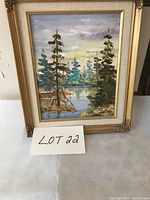 Front view of framed oil landscape painting showing pine trees by water, with visible signature in bottom left.