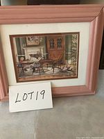 Framed print showing an interior scene with a woman reading, chairs, cat, detailed home furnishings, pinkish wooden frame and white matting around the artwork.