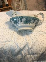 Side angle of vintage Mellor Taylor gravy boat showing overall shape, handle, and blue floral pattern.