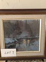 Photo showing framed winter scene print with snow-covered trees, river, and wooden frame.