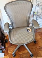 Front view of gray mesh office chair showing seat, back, armrests and caster wheels