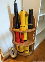 Photo of 12 assorted flashlights arranged on a wooden corner shelf, showing color and shape variety