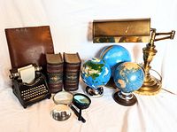 Overview of all items showing leather cover, typewriter paperweight, bookends, magnifying glasses, globes, desk lamp, and gloves.