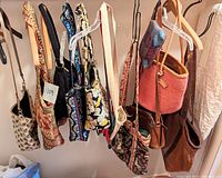 Photo showing 11 purses and bags hanging on a rack, featuring a variety of colors, fabrics, and designs.