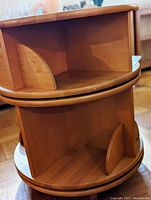 Close-up image of lower and upper shelves showing compartments separated by wooden dividers and the rotating circular frame.