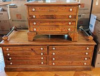 Full view of the small 4-drawer dresser sitting on the larger 4 door double sided drawer chest, showing both matching decorative motifs and porcelain knobs.
