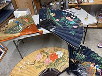 Overview of fans arranged on table and floor showing scale and variety