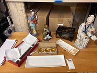 Full view of table with porcelain figurines, lacquer box, serving plates and bowls boxed set