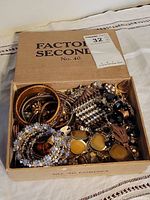 Top-down view of box showing assorted bracelets, necklaces, earrings, and brooch.