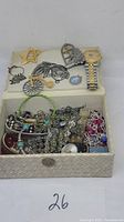Box with assorted mixed costume jewelry including sterling charms and a wristwatch