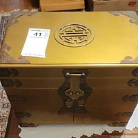 Front view of the gold and brass Asian style large jewelry box showing the lock and corner hardware.