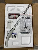 Open box showing the steamer's handle, red and white steamer unit, and packaged parts