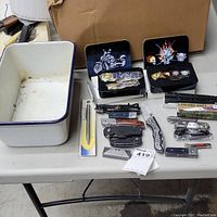 Full view of all items on table including porcelain container and grouping of knives and cutters with decorated cases