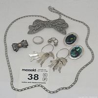 Full view of jewelry lot showing sterling silver earrings, a ring, two bow pins, and a silver tone chain necklace with marcasite stones.