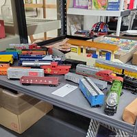 Overview of various toy trains and accessories on table showing multiple locomotives and freight cars.