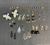 Top-down view of all vintage black and white themed costume jewelry items featuring earrings and a bracelet.