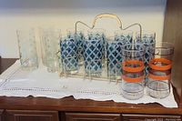 Front right profile of the full grouping showing all glasses and carrier on cloth atop wooden furniture