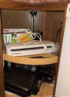 Photo of FoodSaver Vac 300 vacuum sealer and George Foreman grill under kitchen cabinet.