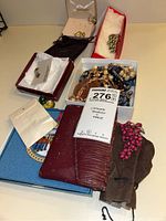 Wide view showing assortment of costume jewelry including multiple necklaces, earrings, and a rosary displayed in boxes and pouches