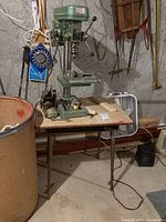 Overall view of the green Alltrade drill press on a table, showing its construction and location.