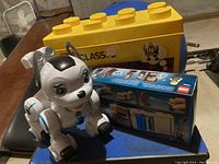 Yellow Lego Classic storage brick with a robot dog toy and sealed Lego set box beside it