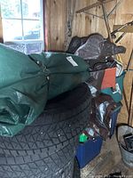 Large green tarp folded on top of stacked tires inside wooden shed