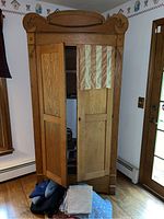 Front view showing two wooden doors partially open with storage inside, patterned fabric hanging in the door.