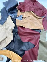 Photo showing assorted irregular leather pieces in maroon, tan, black, beige, and grey-blue colours, layered and slightly overlapping.
