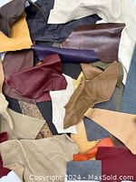 Leather pieces spread out on a surface showing variety of colors, textures, and irregular shapes.