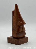 Front angled view of the wooden eyeglasses stand showcasing the nose and lips design on a block base.