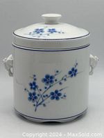 Front view of white ceramic canister with blue floral decoration and lid