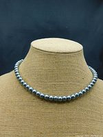 Front view of single strand silver/grey pearl necklace on display bust.