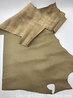 Photo showing irregular shaped taupe leather hide laid flat, both front and back visible revealing texture and color.