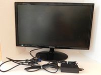 Front view of the Samsung 23-inch Full HD LED monitor with power and VGA cables laid in front of the screen.