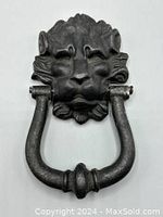 Front view showing detailed lion's head holding a ring knocker in metal black finish.
