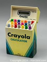 Front view of Crayola calculator with flip top open showing colorful crayon tip buttons and calculator screen inside crayon box design.