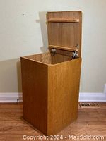 Image of open flip top showing the inside compartment and the attached lid with metal hinges and support arm.