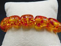 Close-up of the translucent yellow-orange Lucite barrel beads with embedded red flecks.