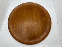 Round teak wood tray plate viewed from above showing circular shape and wood grain.